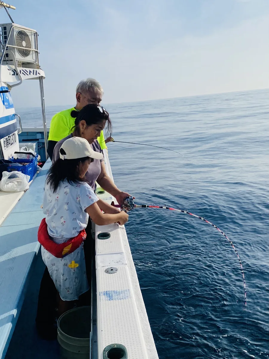竿を大きく曲げて魚とやり取りする双葉ちゃんと、見守る保護者・スタッフ