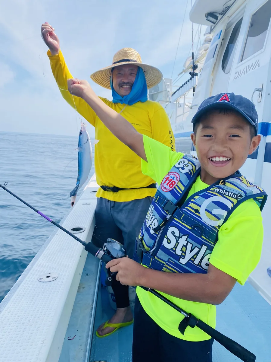 釣り上げた魚を掲げてガッツポーズする海玄くんと引率スタッフ