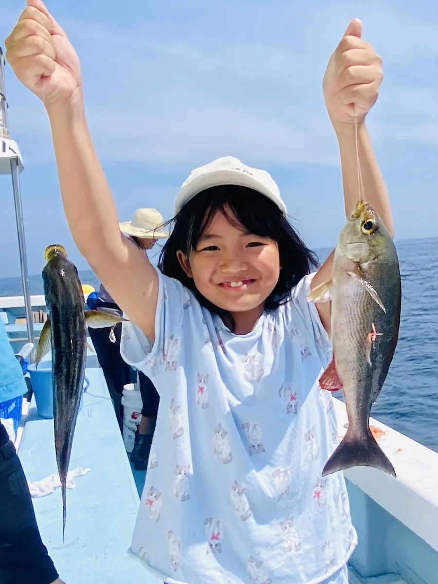 両手に一匹ずつ魚を持って笑顔を見せる双葉ちゃん