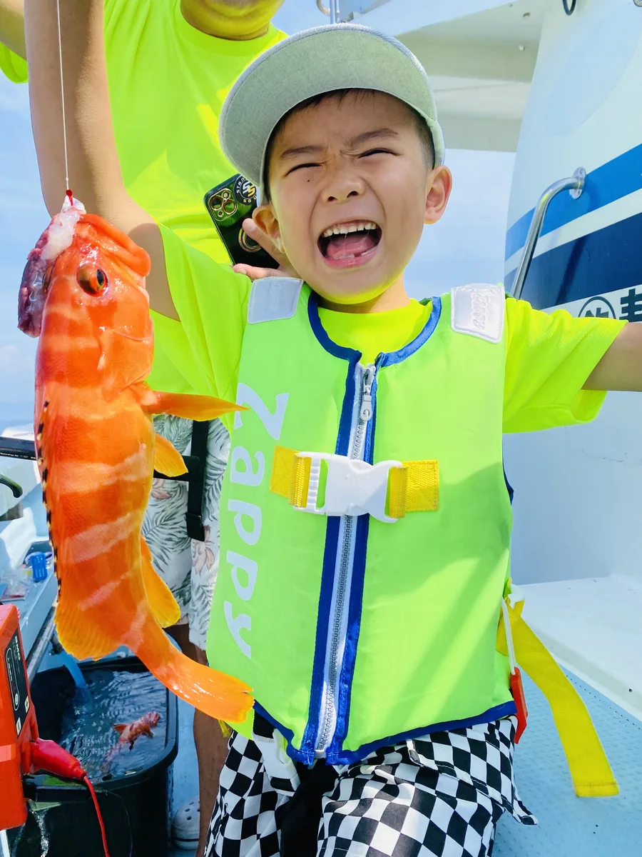 鮮やかなオレンジ色のハタを釣り上げて驚く葵葉くん