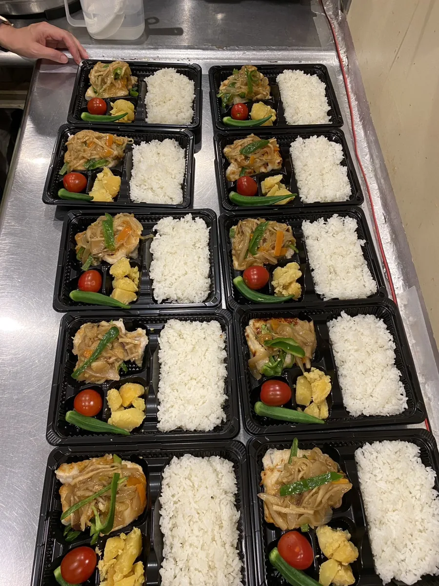 Rows of bento boxes filled with marlin in thickened ankake sauce, lined up in the kitchen